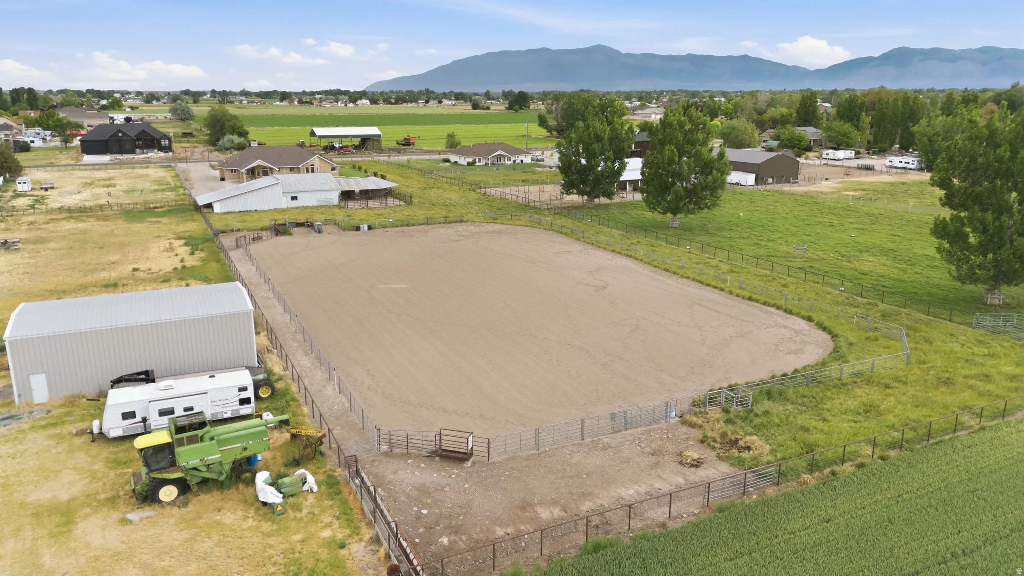 Expansive fenced riding arena with a large metal outbuilding