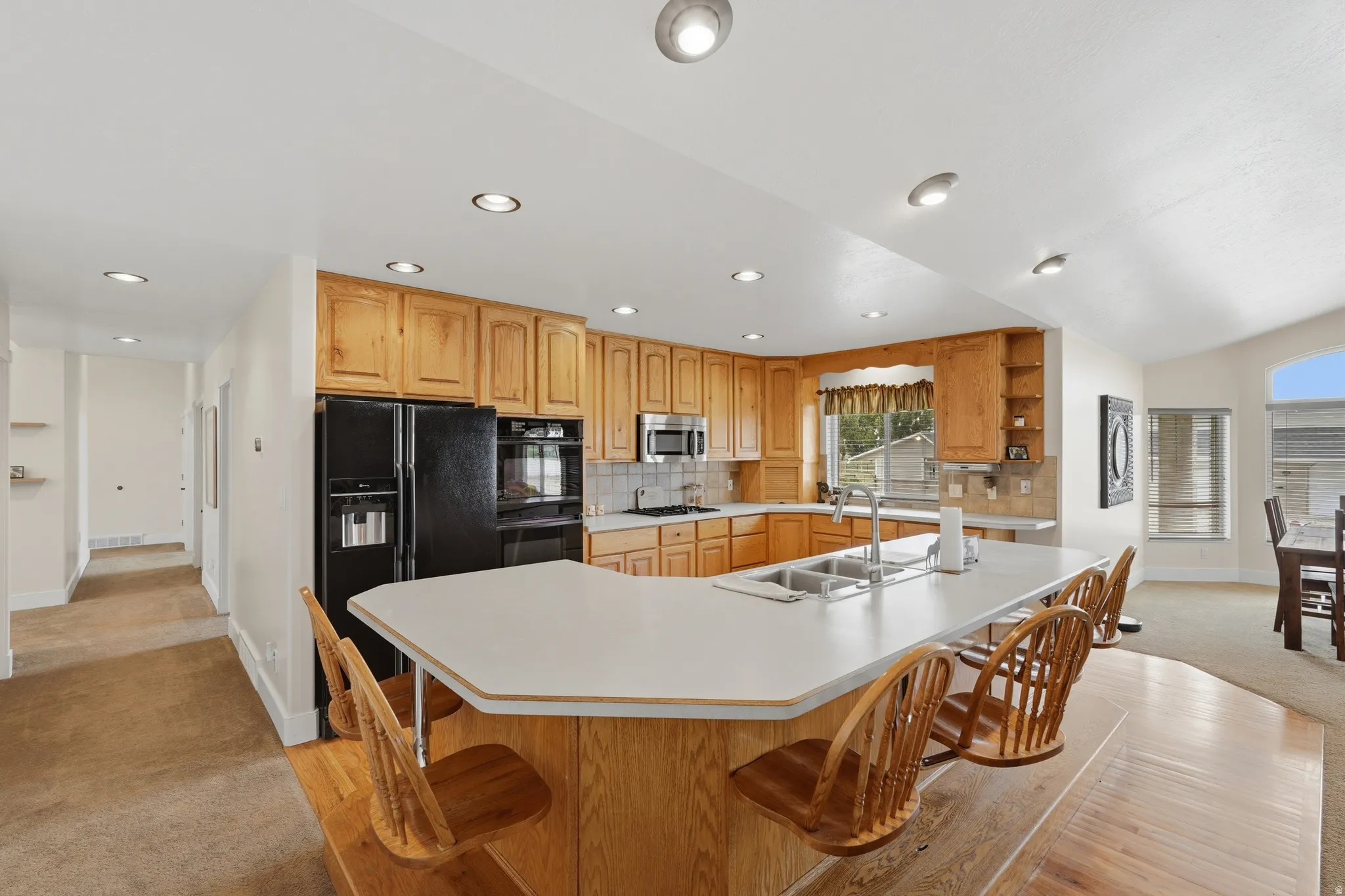Kitchen with light wood cabinetry, white countertops, a built-in oven, and a stainless steel double sink