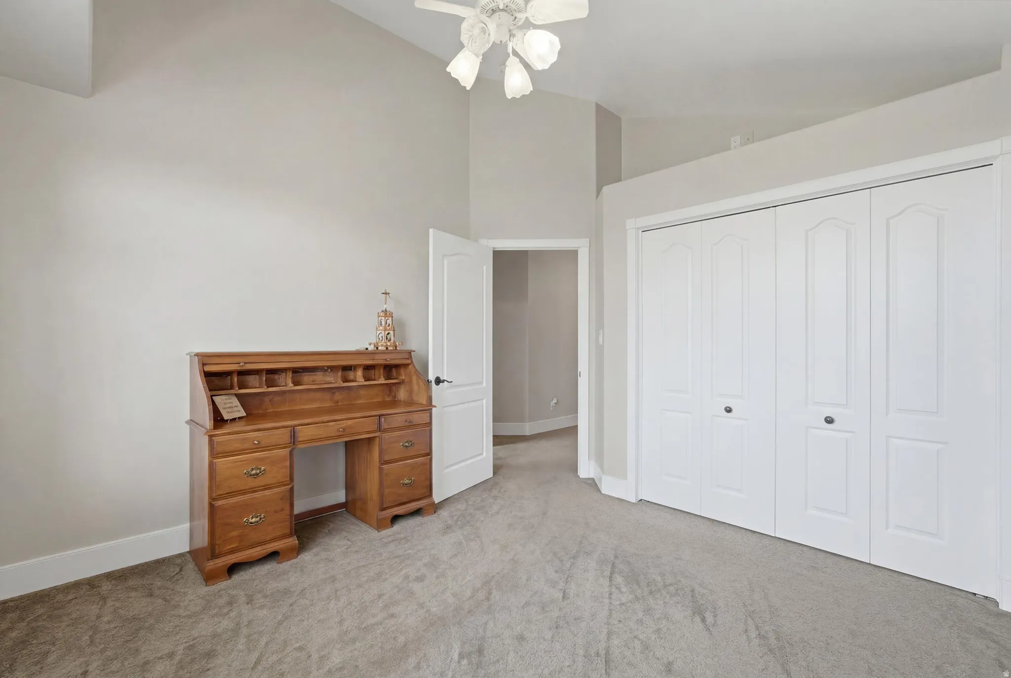 Room featuring vaulted ceilings, plush carpet flooring, and a ceiling fan light fixture