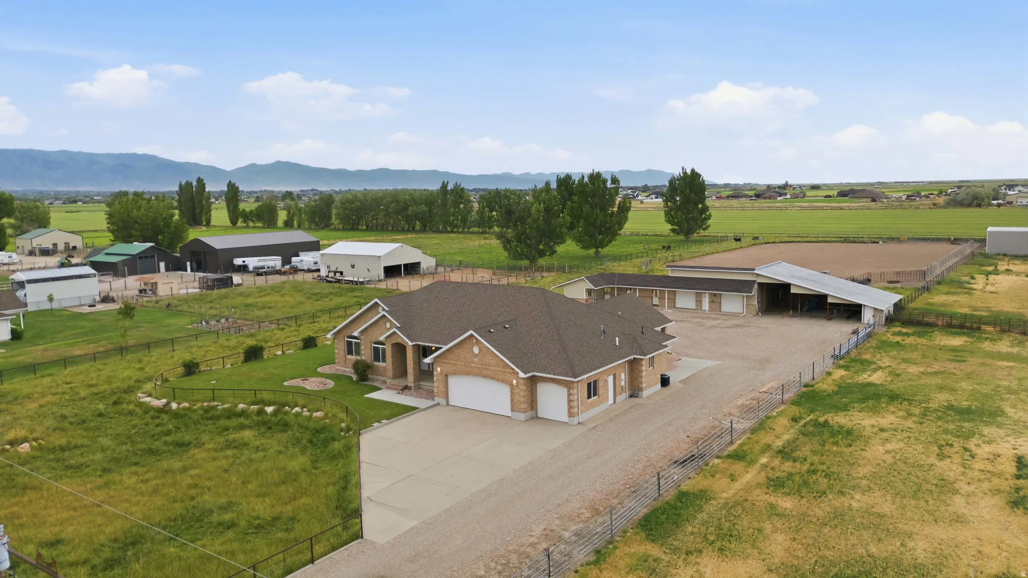 Expansive property featuring a single-story residence with a two-car garage, multiple outbuildings, and an equestrian arena
