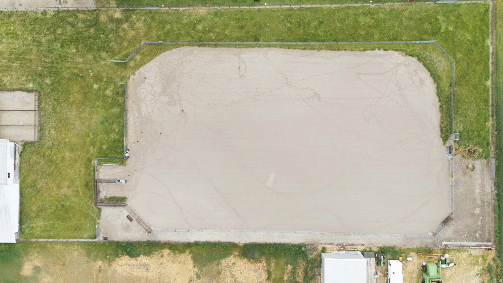Expansive sand arena with perimeter fencing, surrounded by green space