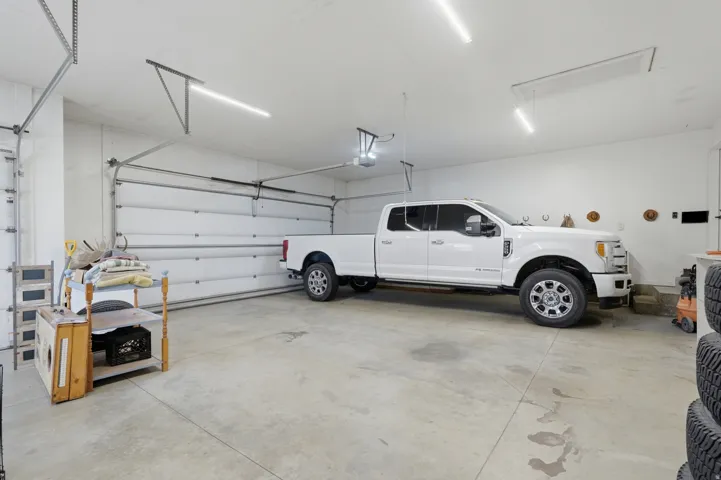 Spacious garage featuring concrete flooring, multiple overhead linear light fixtures, and two overhead garage doors