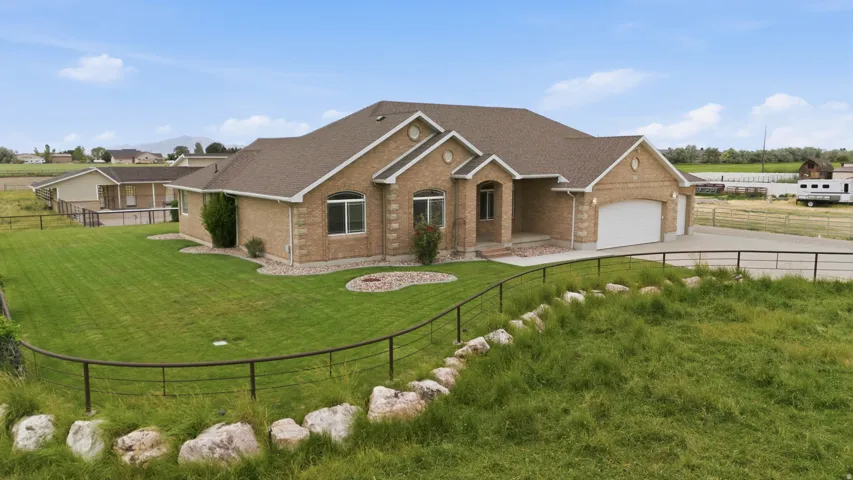 Brick exterior residence featuring an attached two-car garage, front yard landscaping, and a fenced perimeter
