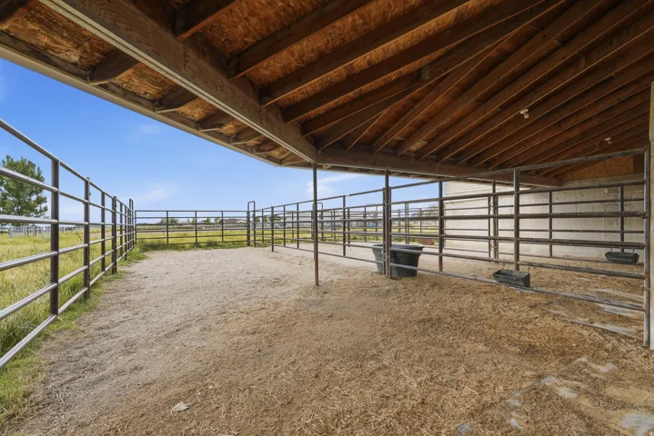 Covered animal pen featuring metal fencing, a high wood-finish ceiling, and a large open-air section