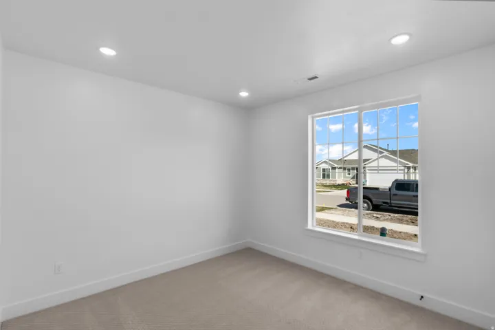 Room featuring a large grid-pattern window, neutral carpeting, recessed lighting, and white baseboards