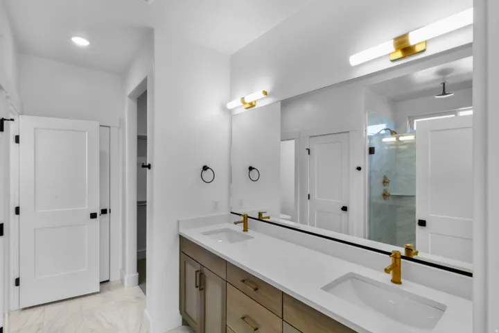 Contemporary bathroom featuring a double vanity with light wood-finish cabinetry and white countertops