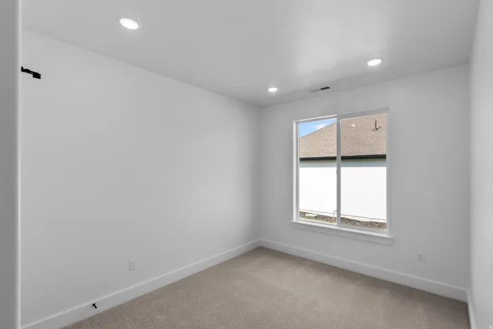 Neutral interior room featuring recessed ceiling lighting, a single window, white walls, white baseboards, and carpeted flooring