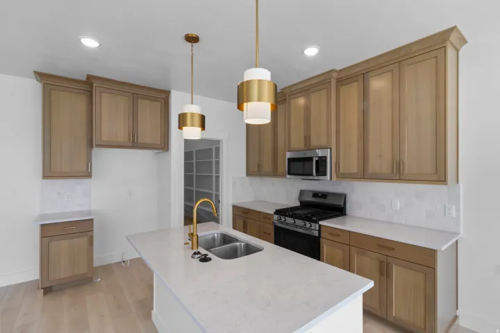 Open-concept kitchen featuring light wood-finish cabinetry, white countertops, and a white tile backsplash