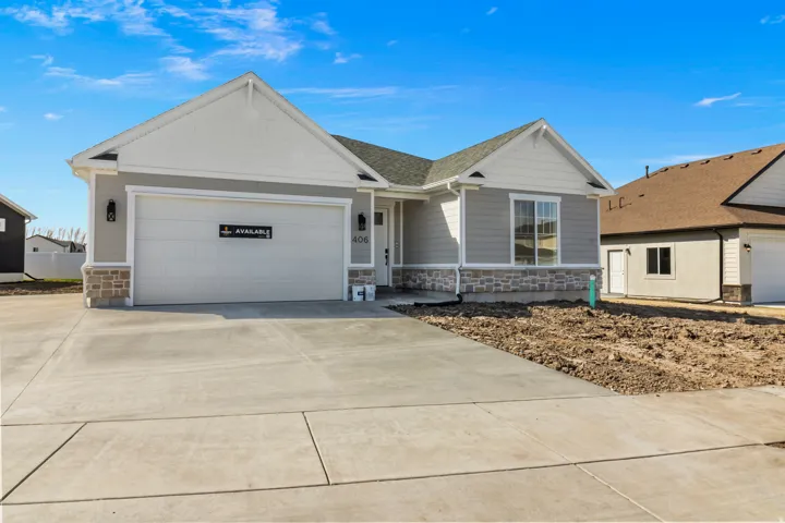 Contemporary ranch-style exterior featuring gray siding, white trim, stone accents, a single-car garage, and a concrete driveway