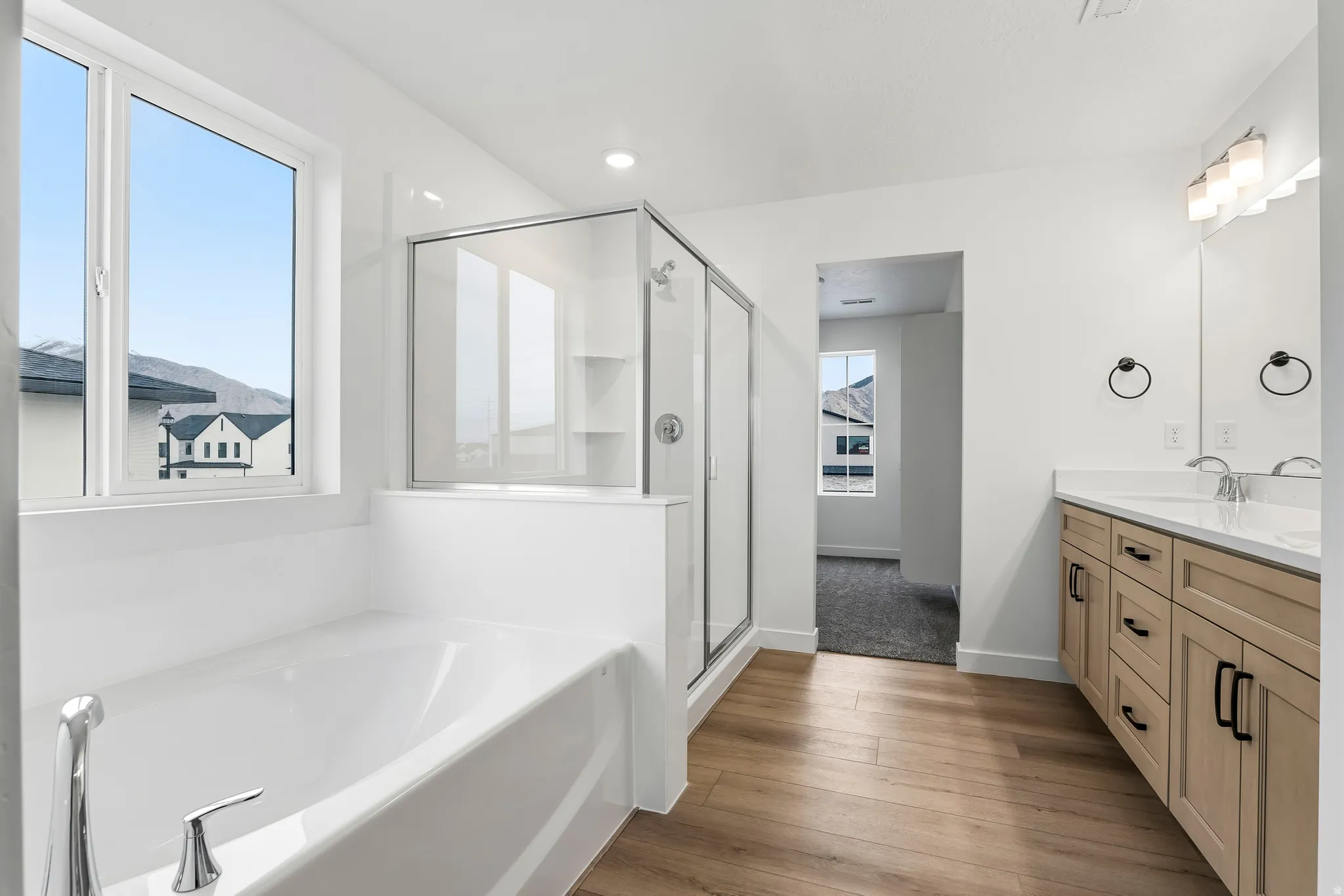 Bathroom featuring a soaking tub, glass-enclosed shower, and wood-finish flooring