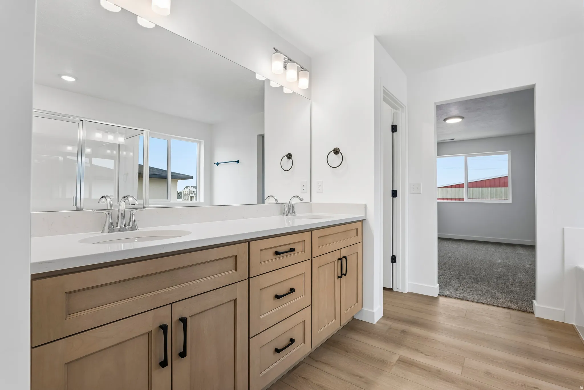 Dual-sink vanity with light wood-finish cabinetry, white countertop, and chrome fixtures