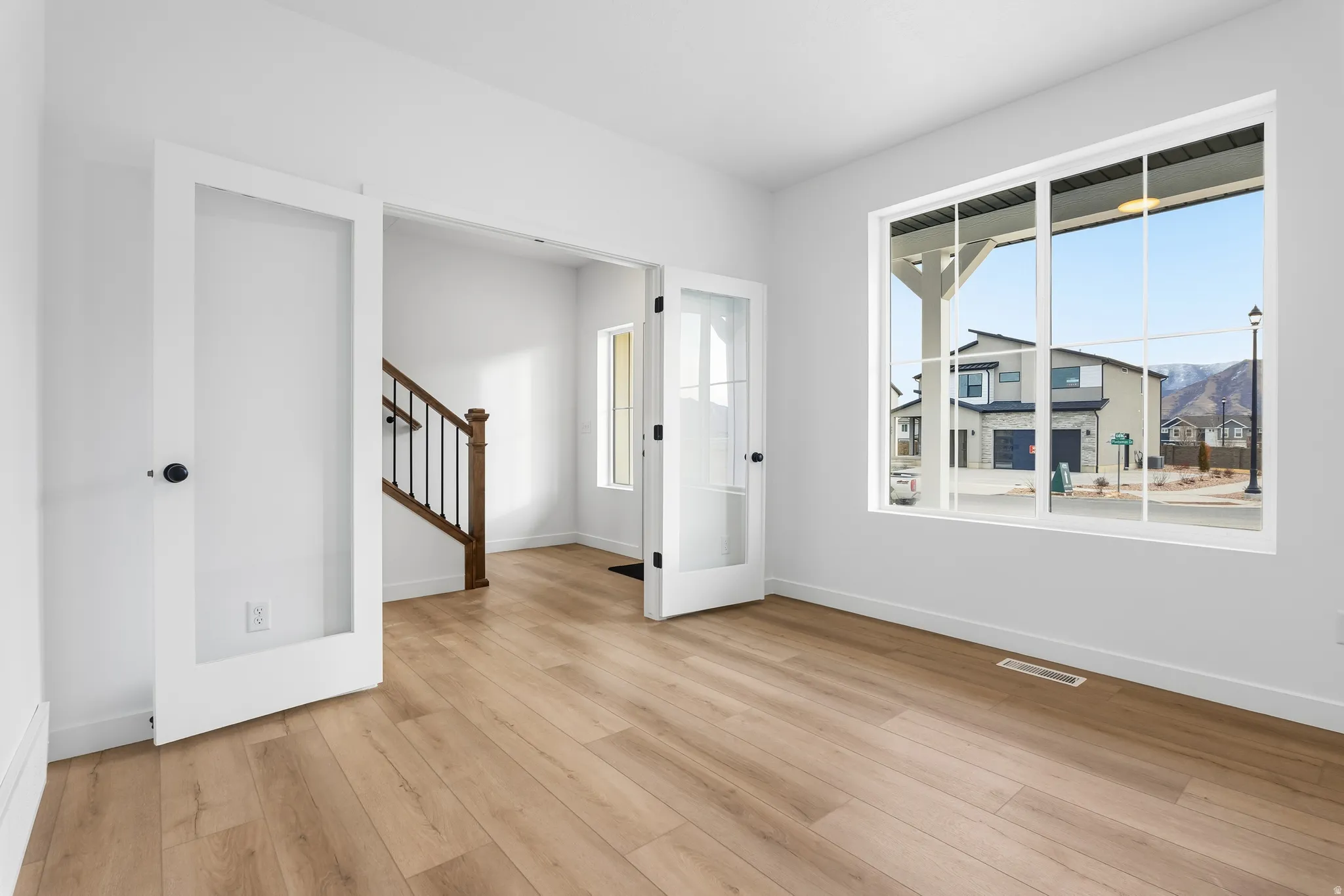 Spacious room featuring wood-finish flooring, white walls, and a large multi-pane window