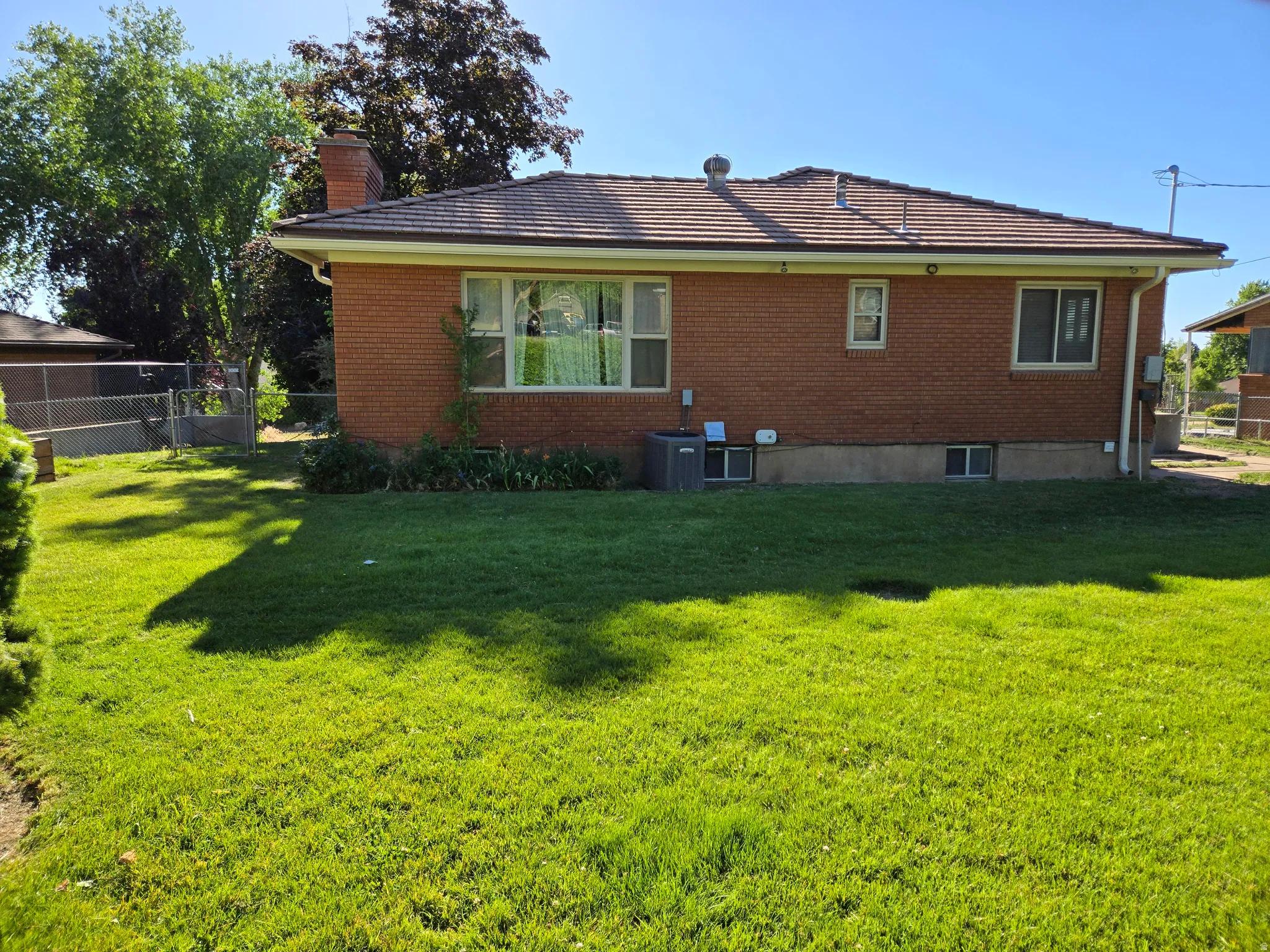Brick exterior with a tiled roof, featuring multiple windows and a green lawn