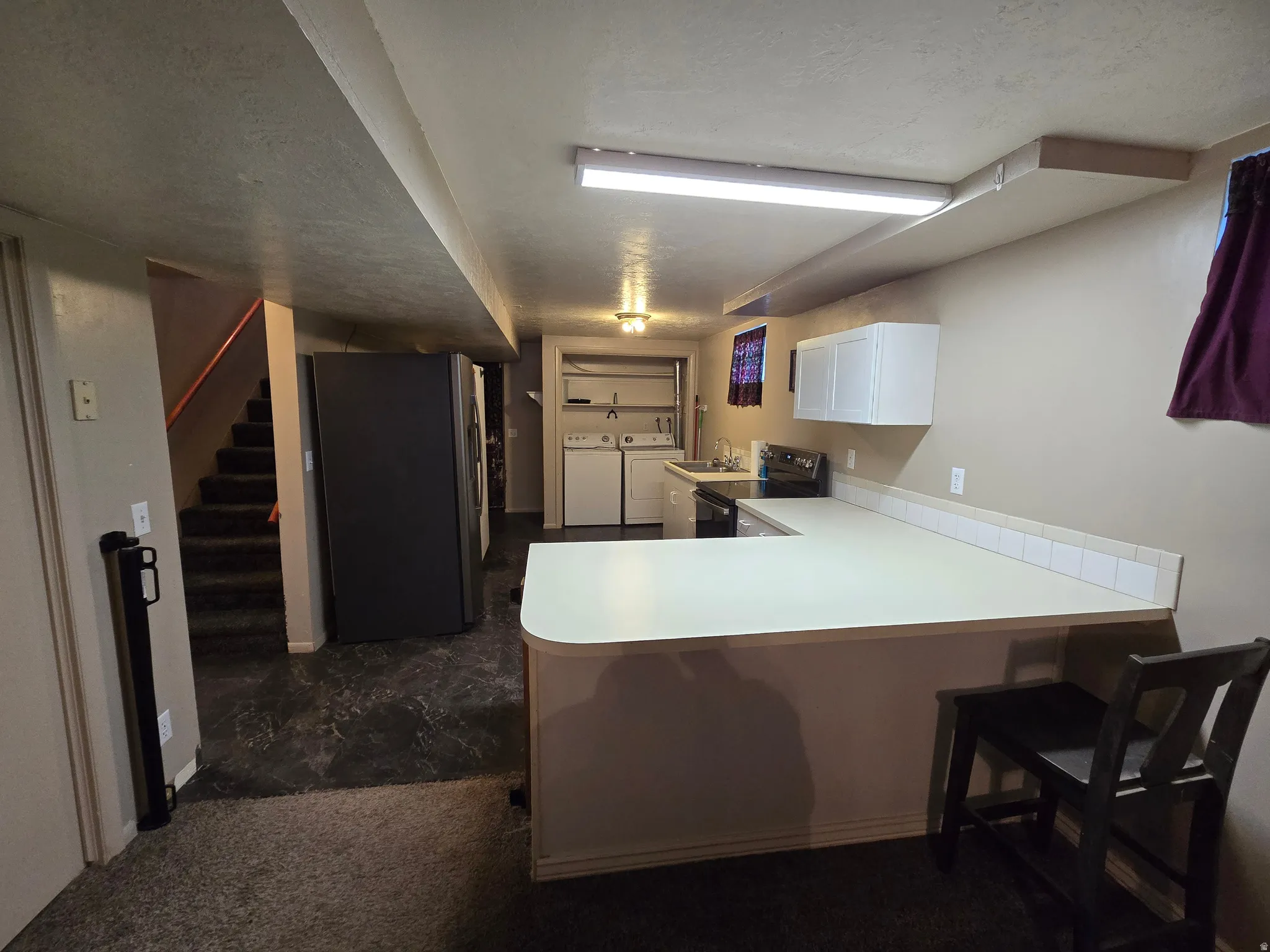 Kitchenette featuring white cabinetry, light-colored countertops, and a white tile backsplash