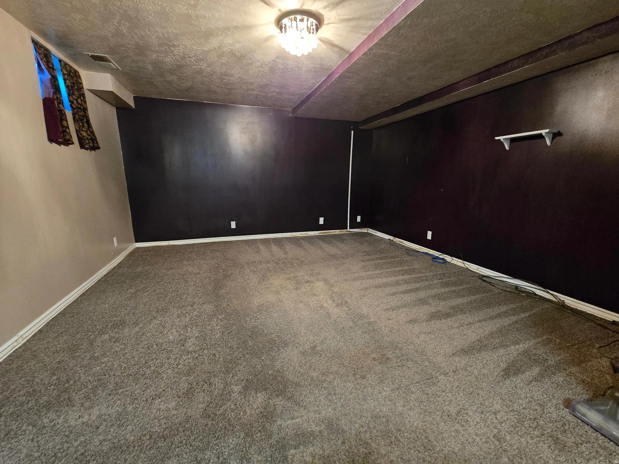 Spacious room featuring dark walls, tan walls, and grey carpet flooring