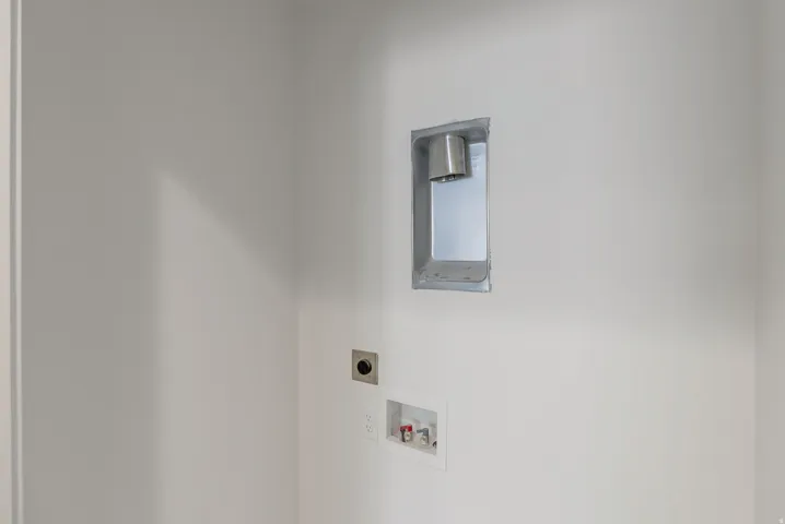 Utility area featuring white walls, a recessed dryer vent, and water hookups
