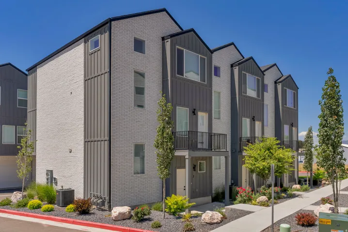 Contemporary townhome exterior featuring light gray brick and dark gray vertical siding