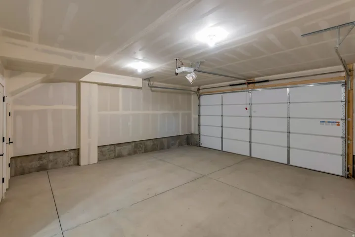 Spacious garage featuring a concrete floor, two overhead light fixtures, exposed ceiling joists, and a sectional garage door