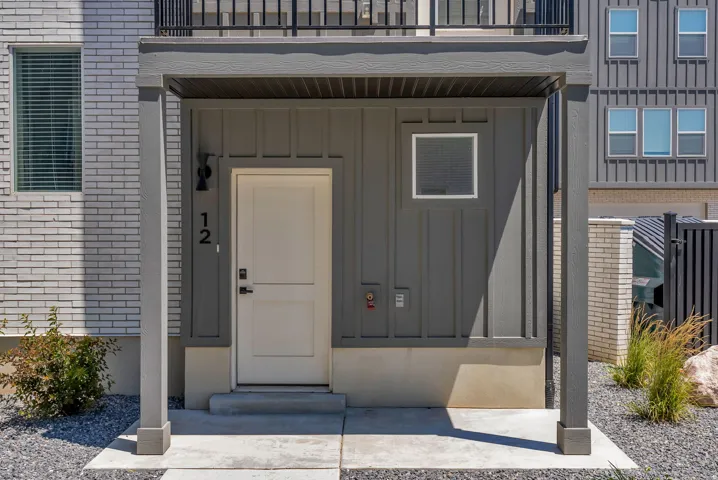 Covered entryway with concrete landing, featuring a white paneled door and board and batten siding