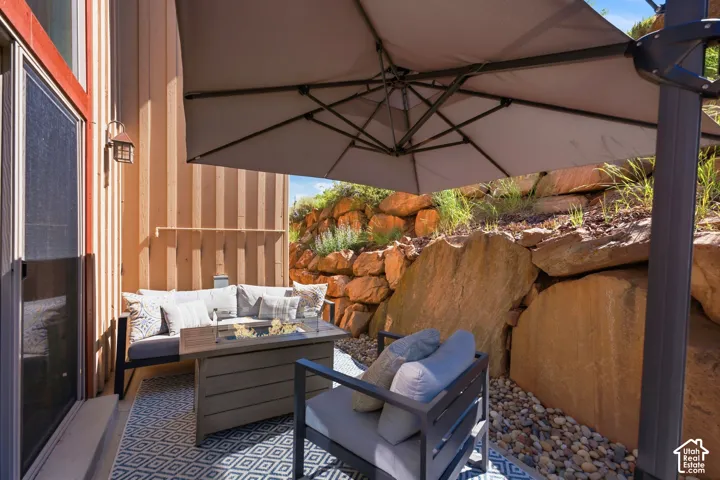 Outdoor patio with a geometric pattern rug, river rock landscaping, and natural rock retaining wall