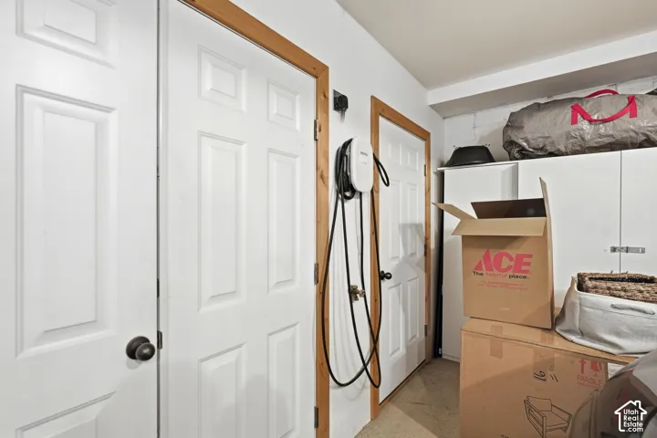 Utility area featuring multiple paneled doors with contrasting wood trim, an installed EV charging station, and built-in white cabinetry