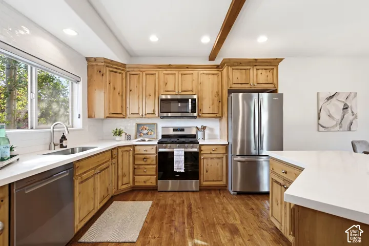 Kitchen featuring natural wood cabinetry, stainless steel appliances, white countertops, and wood-finish flooring