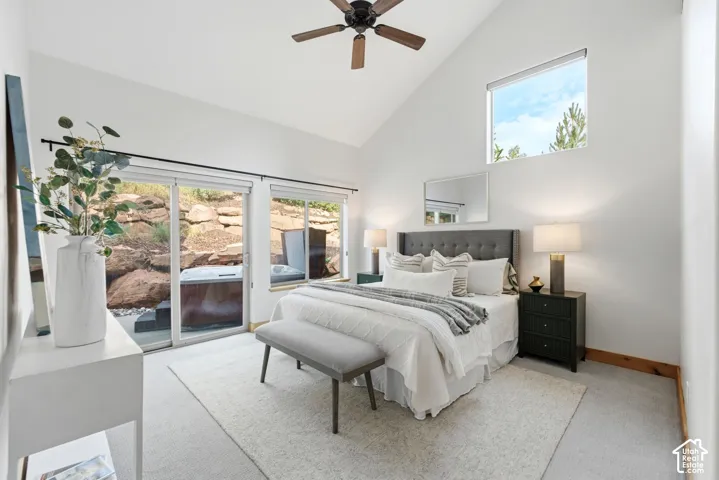 Vaulted ceiling bedroom featuring sliding glass doors opening to an outdoor area with a hot tub