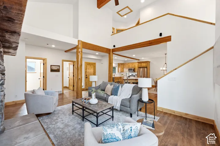 Vaulted ceiling living room featuring exposed wood beams and wood-finish flooring