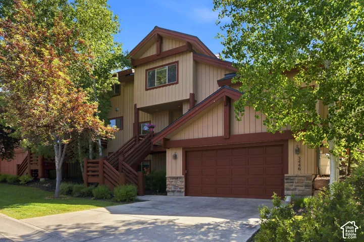 Multi-level exterior with a two-car garage, stone accents, and wood-toned siding