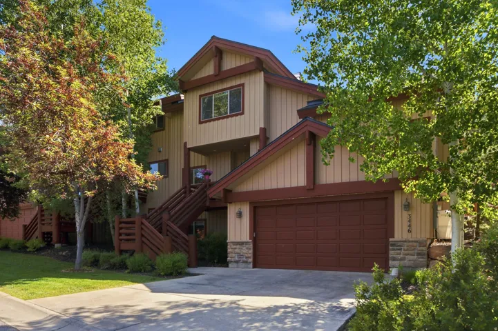 Multi-level exterior with a two-car garage, stone accents, and wood-toned siding