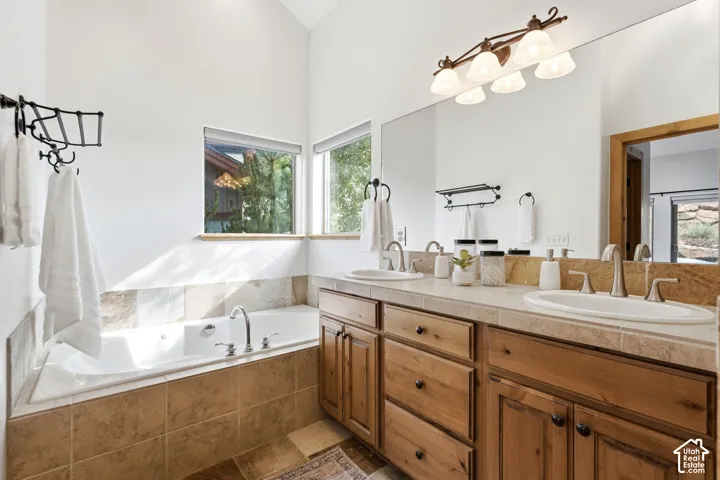 Bathroom featuring a built-in soaking tub, dual vanity with undermount sinks, and natural wood cabinetry