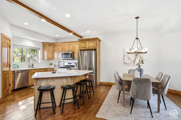 Open-concept kitchen and dining area featuring wood-finish flooring, recessed lighting, and a prominent wood beam