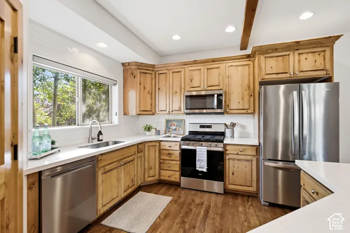 Kitchen featuring natural wood cabinetry, white countertops, stainless steel appliances, and wood-finish flooring