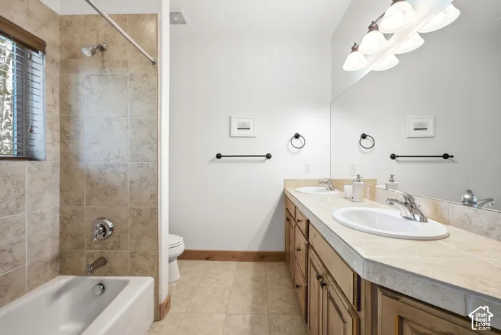 Bathroom featuring a double vanity with integrated sinks, a full-width mirror, and a five-light fixture