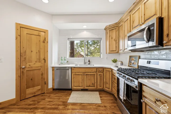 Kitchen featuring wood-finish flooring, custom wood cabinetry, and stainless steel appliances