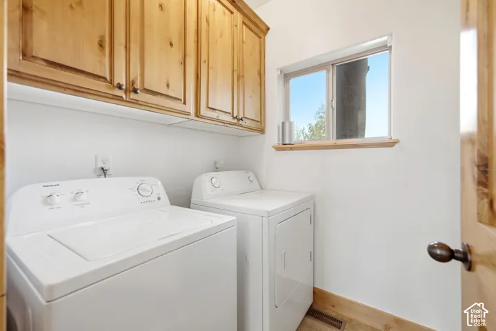 Laundry area featuring light wood-finish cabinetry, a window with wood trim, and wood-finish baseboards