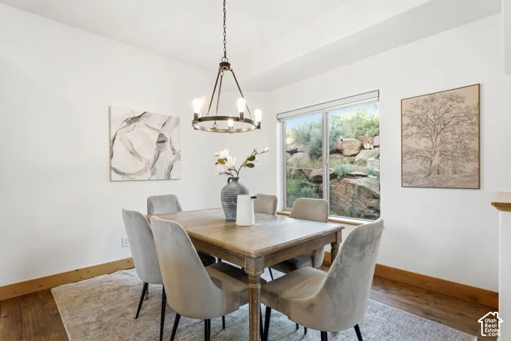 Dining area featuring a contemporary chandelier, large picture window, light wood-finish flooring, and white walls