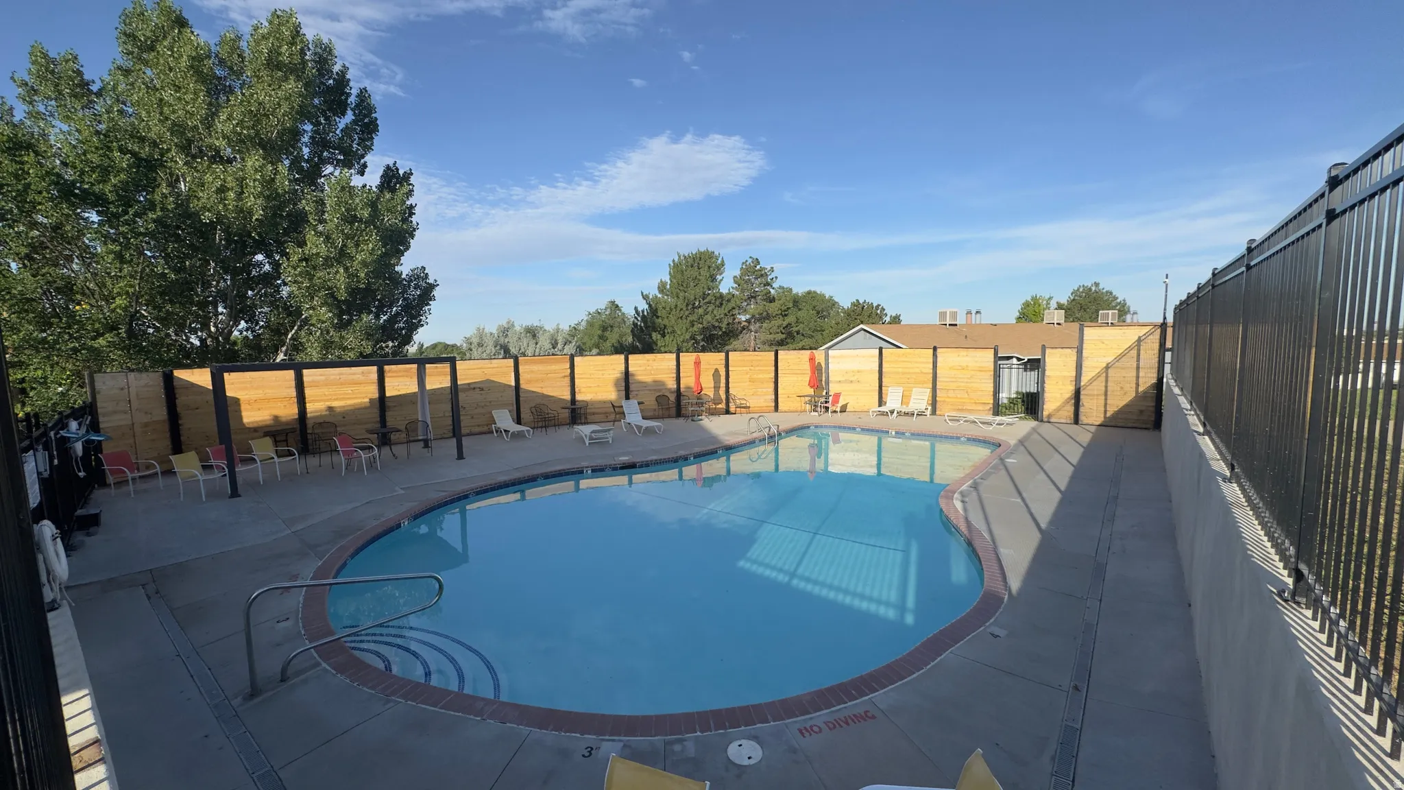 Resort-style community outdoor swimming pool with integrated steps and perimeter fencing.