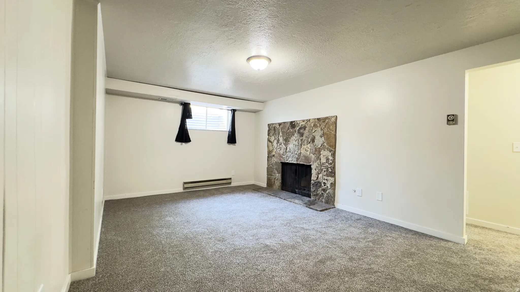 Basement, spacious family room featuring a wood burning stone-clad fireplace and new carpet.