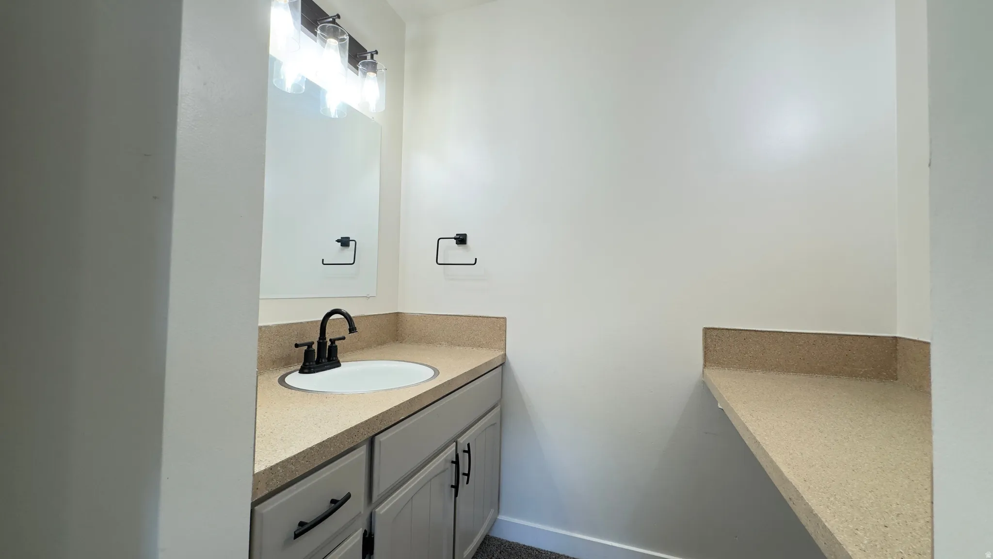 Primary Bedroom vanity featuring excellent lighting and a sink with matte black fixtures, and coordinating cabinetry.