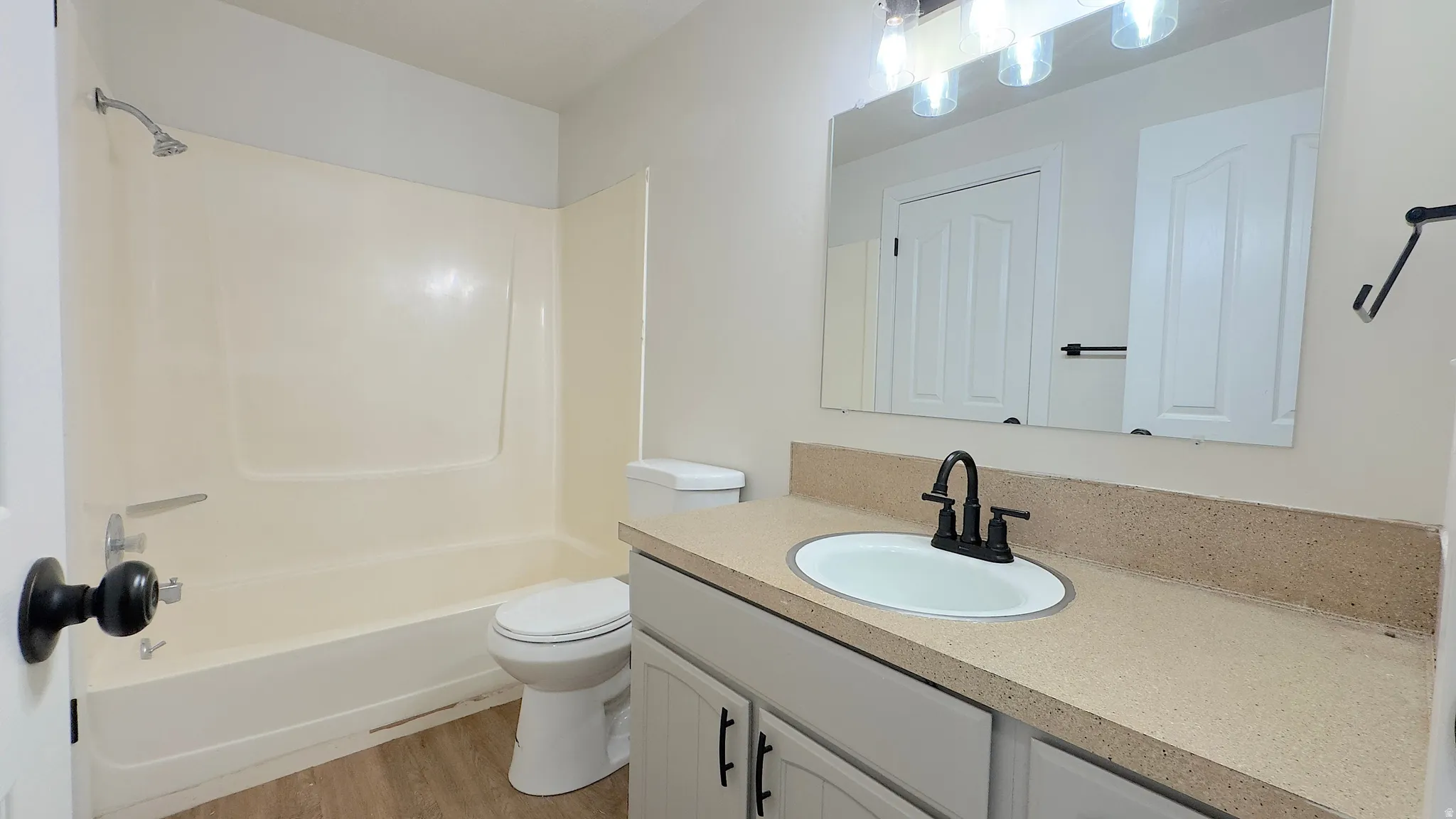Bathroom featuring a single vanity with a solid surface countertop, an undermount sink, and a black-finish faucet