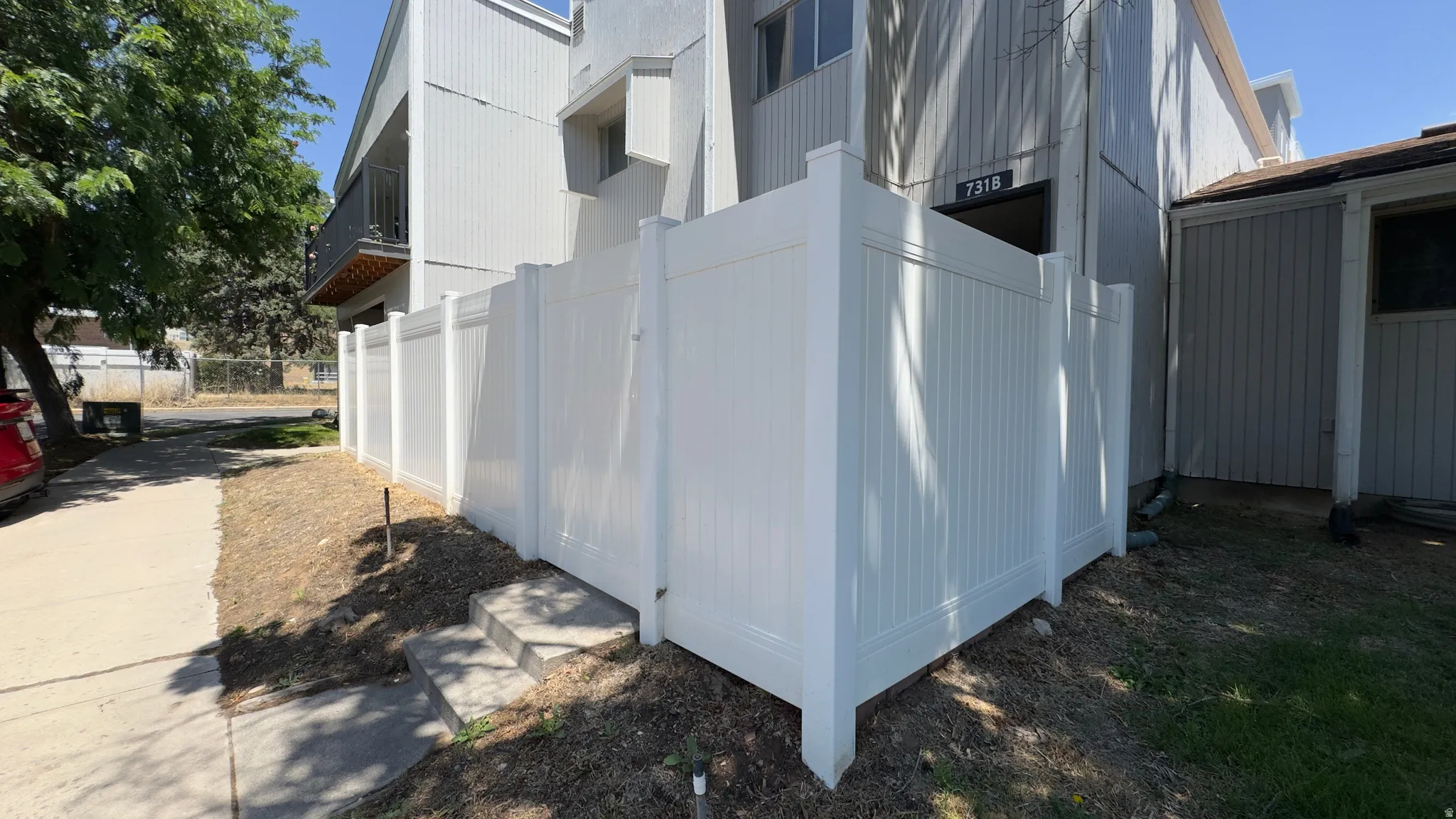 Front entrance, white privacy fencing enclosing a ground-level patio area.