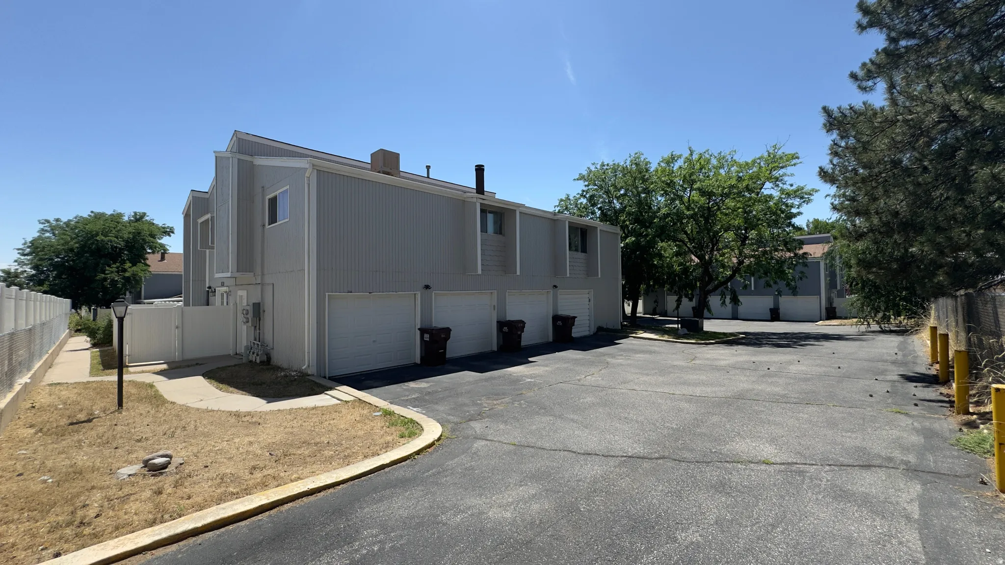 Two-story multi-unit structure featuring vertical panel siding and individual garage access.