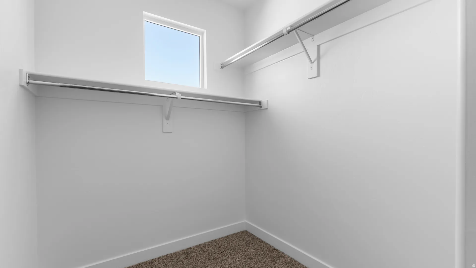 Walk-in closet featuring a window, built-in shelving, and metal hanging rods
