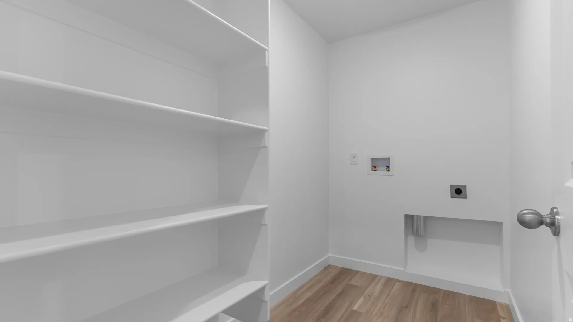 Dedicated utility area featuring wood-finish flooring, white baseboards, and built-in wall shelving