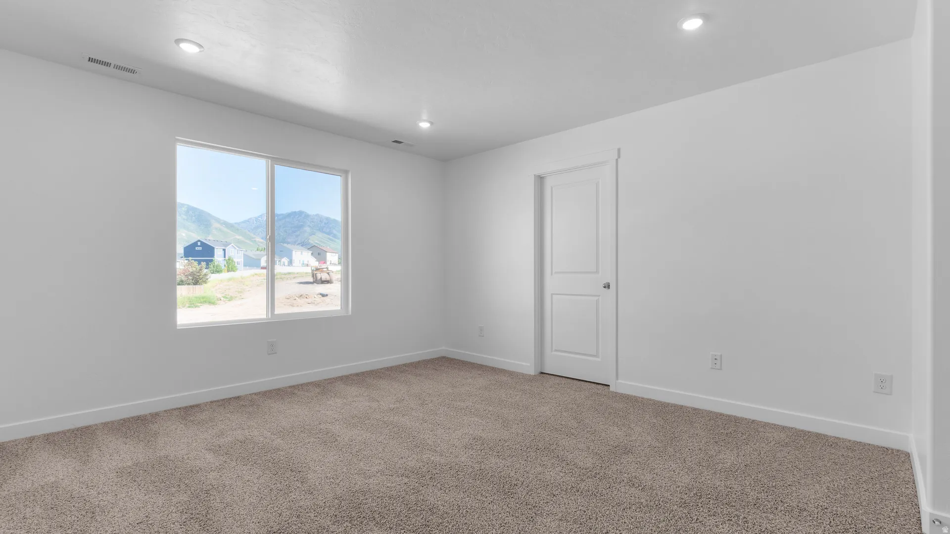 Spacious room with plush carpeting, recessed lighting, and a large window offering mountain scenery