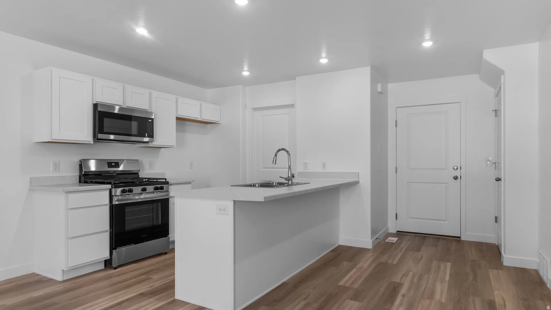 Modern kitchen featuring white cabinetry, light-toned countertops, and stainless steel appliances