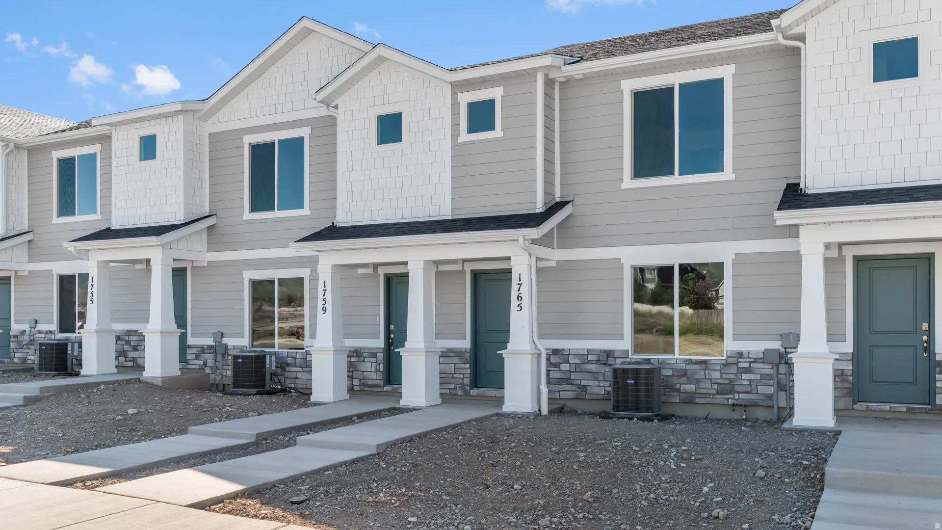 Contemporary townhouse exterior featuring light gray siding with white shake accents