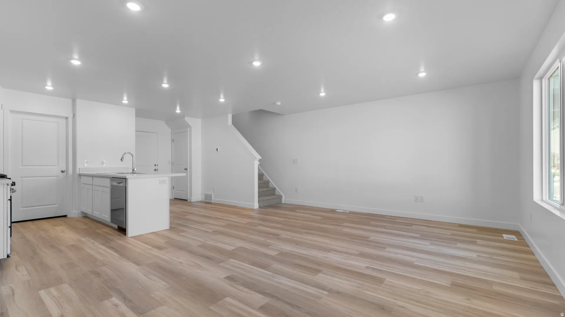 Open-concept living space with wood-finish flooring, recessed lighting, and white trim