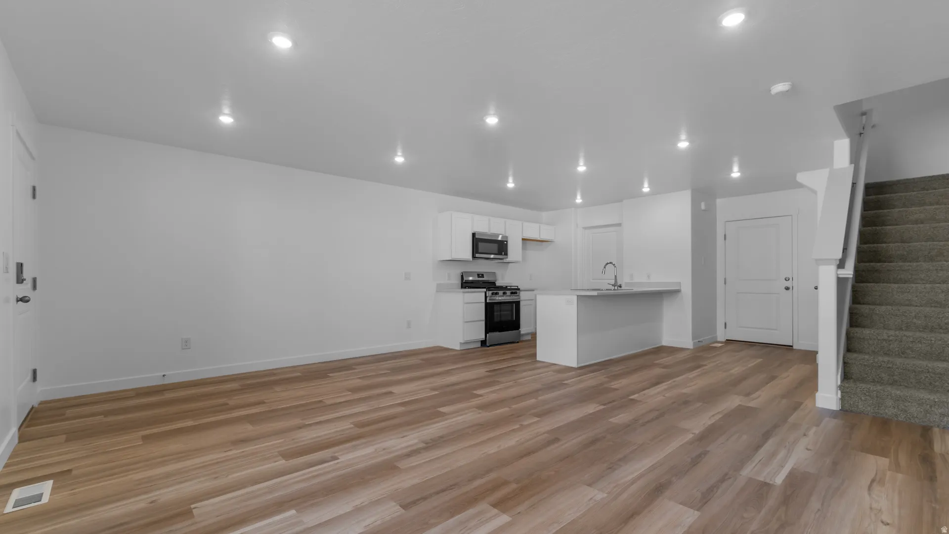 Open concept living space featuring wood-finish flooring, recessed lighting, and a modern kitchen